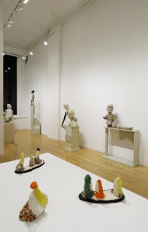 pedestal with 5 sculptures and 4 other sculptures against the wall
