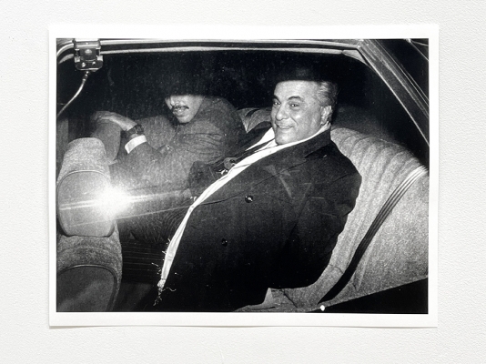 black & white flash photo of man in back of car
