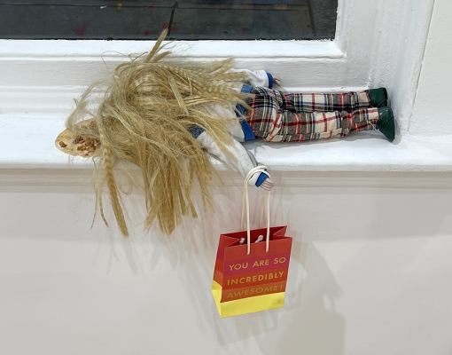 doll with blonde hair laying on windowsill 